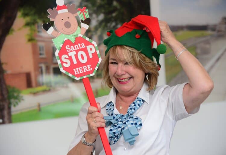 A David Wilson Homes sales advisor with a Santa Stop Here sign