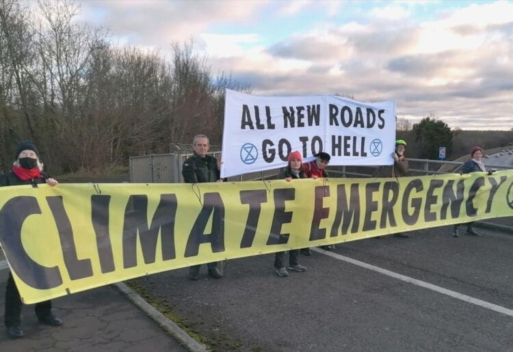 Extinction Rebellion protestors with their climate emergency banner on the footbridge over the M4 by Shinfield this morning Picture: Steve Smyth