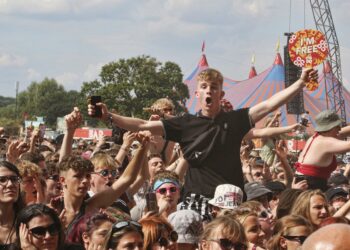 A festival attendee singing and holding a phone