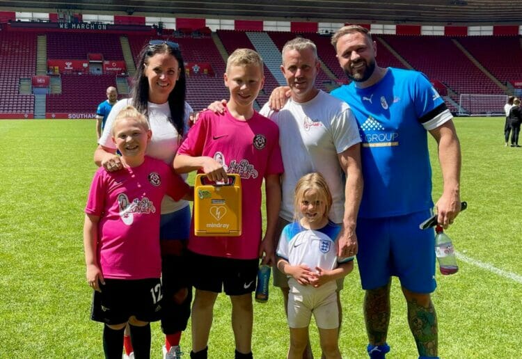 Neil Humphries, second from right, and one of the many defibrillators his charity has distributed