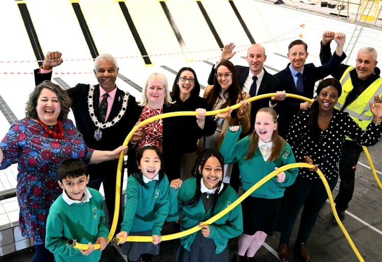 Ready to be filled: Students from Oxford Road Community School with councillors and representatives from GLL Leisure and Pellikaan UK celebrate the start of filling the new swimming pool at Rivermead Leisure Centre