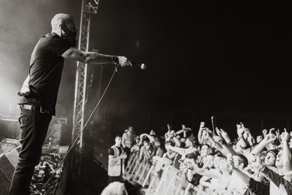 Scroobius Pip stands at the edge of a stage, left, holding a microphone out to a crowd, on the right. Picture taken at Indiependence festival in Cork in 2014 by Dara Munnis.